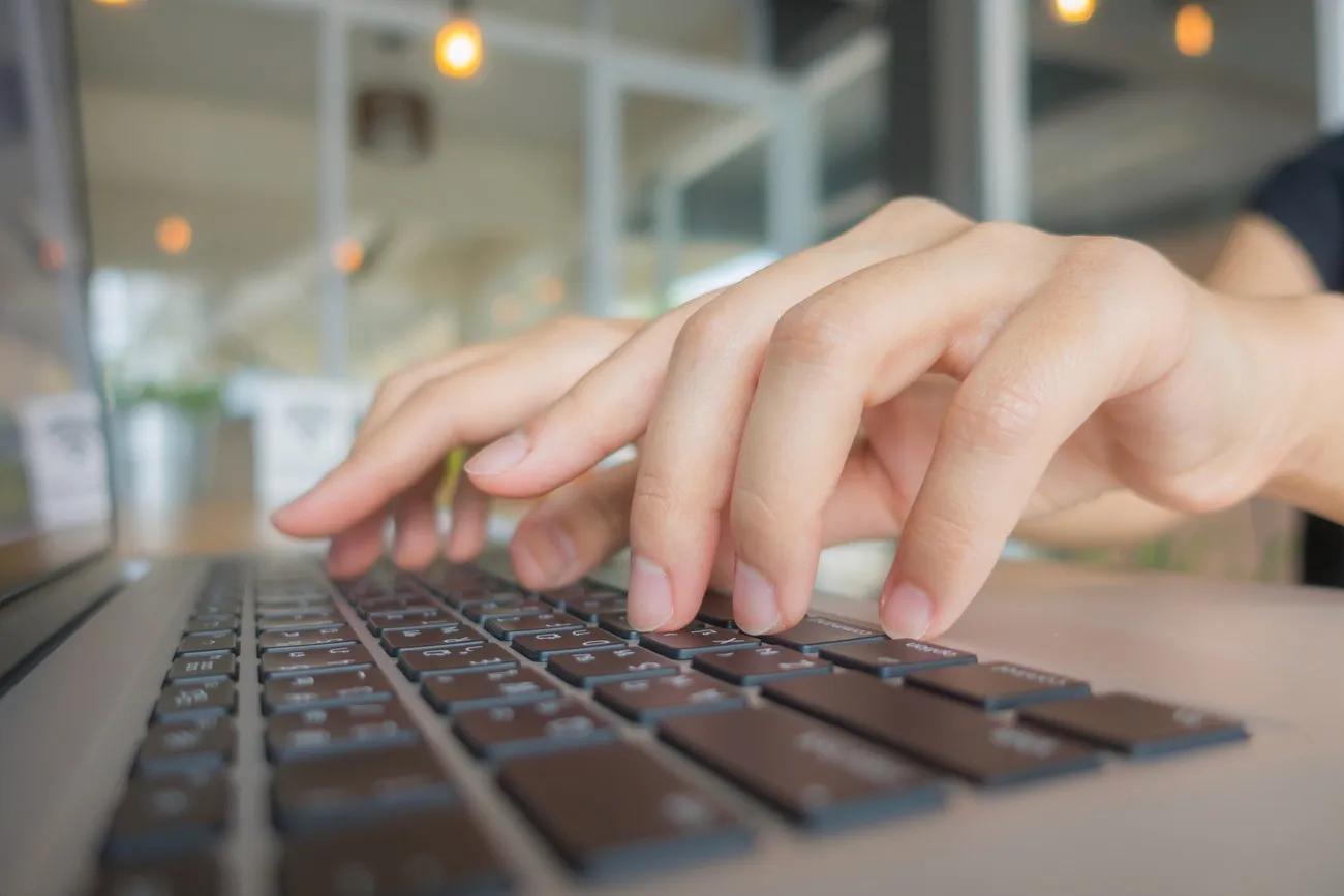 Close de mãos usando teclado com luzes de tecnologia ao fundo