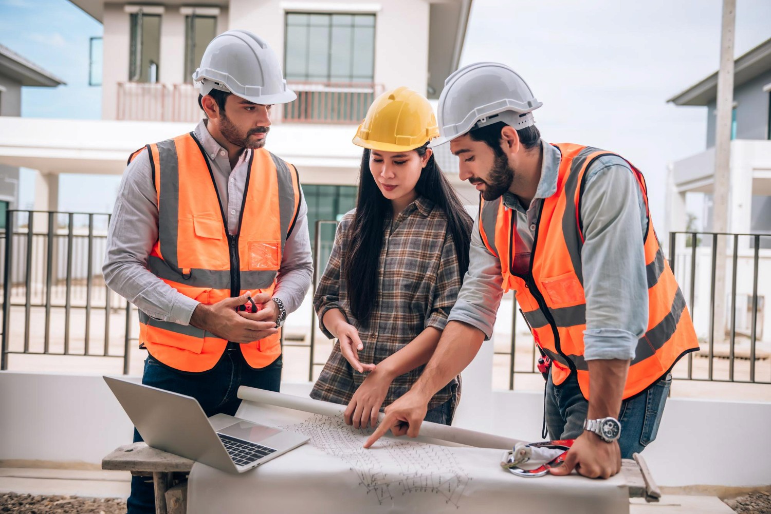Dois profissionais de capacete e colete observando fachada de prédio comercial em construção