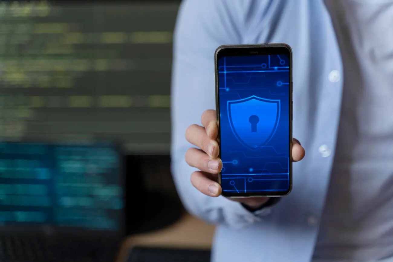 Pessoa segurando um smartphone com ícone de segurança na tela, representando autenticação e certificado digital ICP-Brasil.