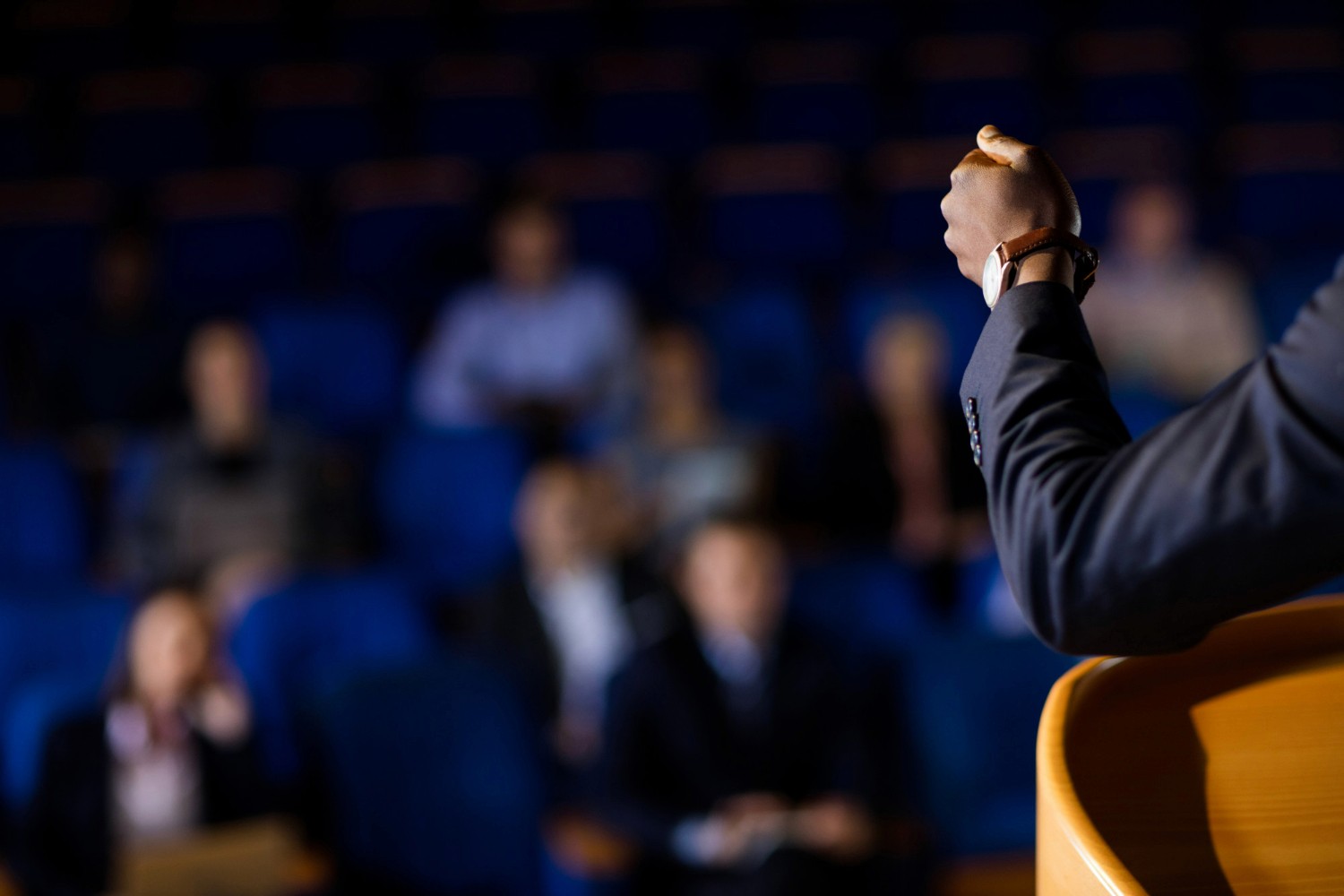 Servidor público discursando em auditório com colegas ouvindo