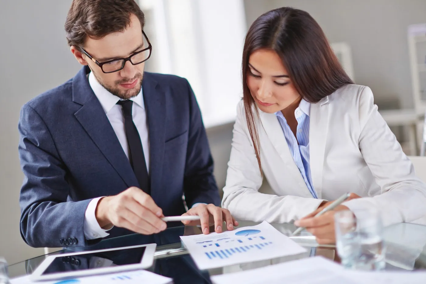 Dois gestores analisando gráficos e documentos financeiros, representando o planejamento e controle exigidos pela Lei de Responsabilidade Fiscal (LRF).