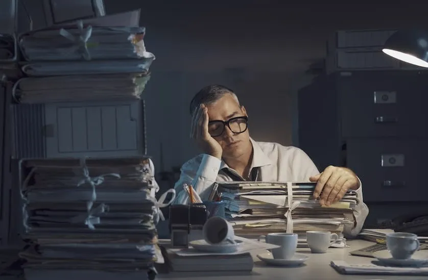 Pessoa analisando relatórios impressos em um escritório administrativo