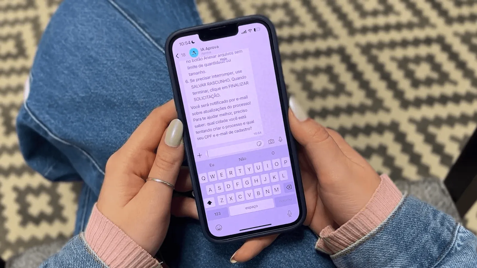 Mulher segura um celular com conversa aberta no WhatsApp,  mostrando instruções para envio de documentos e finalização de solicitação.