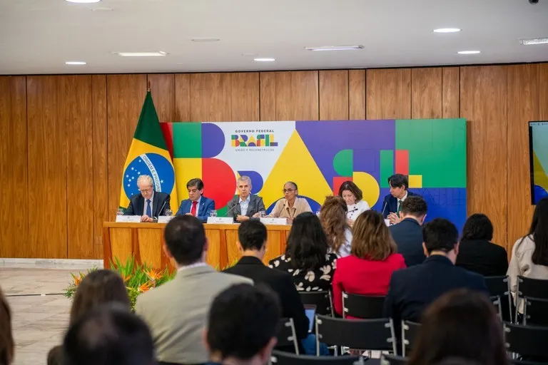 Autoridades do governo federal participam de coletiva de imprensa em Brasília, sentadas à mesa diante de painel colorido com a palavra 'Brasil' e a bandeira nacional ao fundo, enquanto jornalistas acompanham o evento. Foto: Henrique Raynal/CC - gov.br 